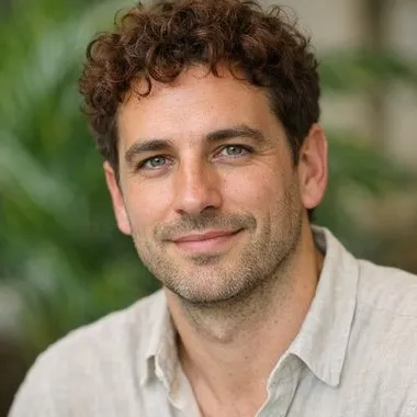 Man in his late 30s with auburn curly hair, light olive skin, green eyes, relaxed expre…